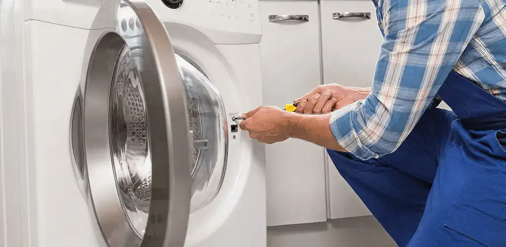 Handyman repairing a clothes dryer and checking electrical connections in Columbia, MO