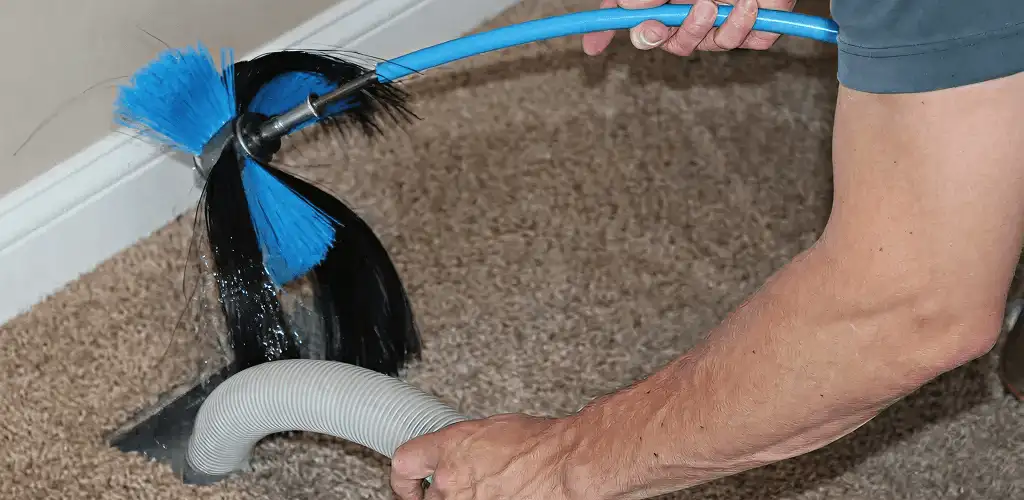 Dryer vent cleaning technician brushing lint from a vent line in Columbia, MO