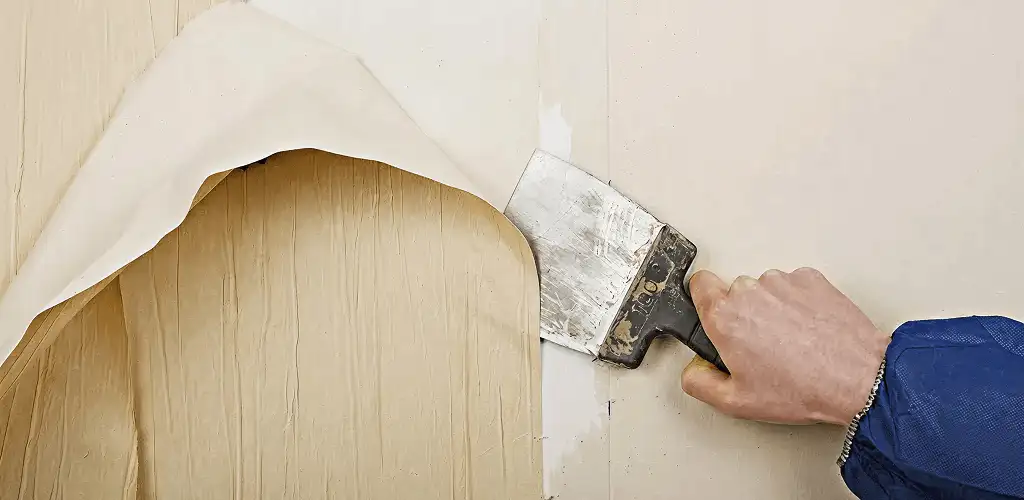 Handyman removing wallpaper with a scraper for wall preparation in Columbia, MO