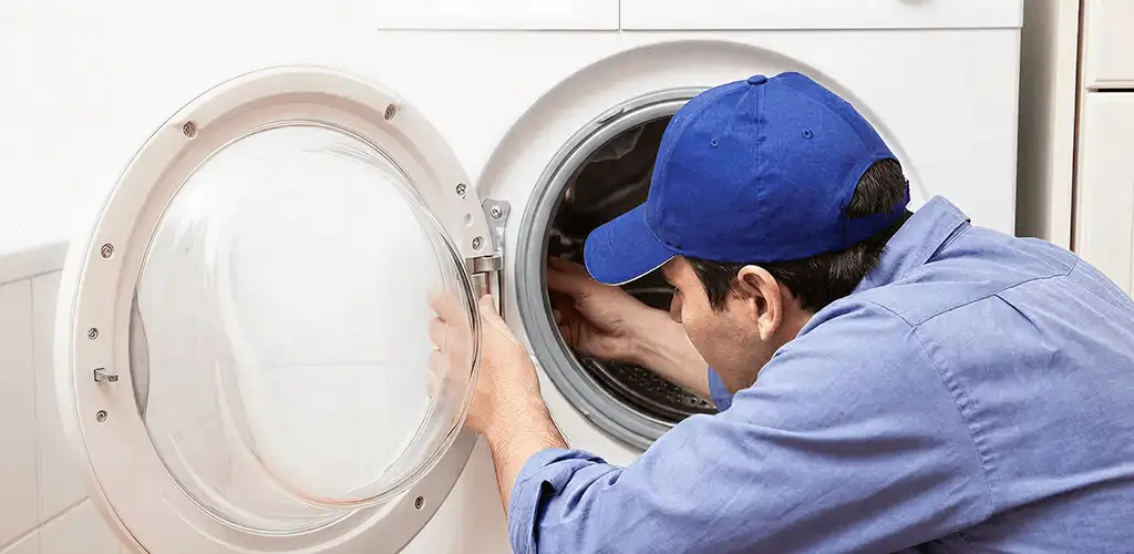 Washing machine repair handyman inspecting a front-load washer drum in Columbia, MO