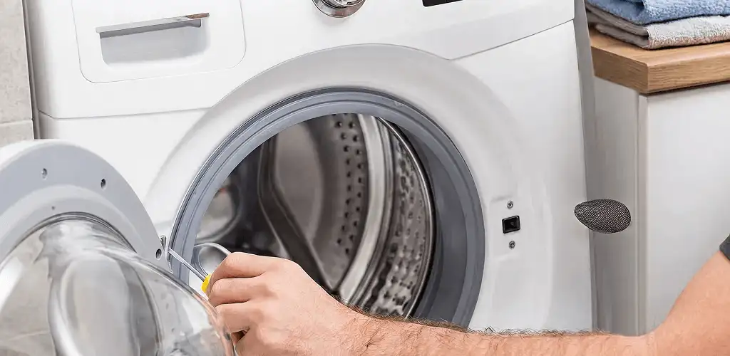 Handyman repairing a front-load washing machine and inspecting the drum in Columbia, MO
