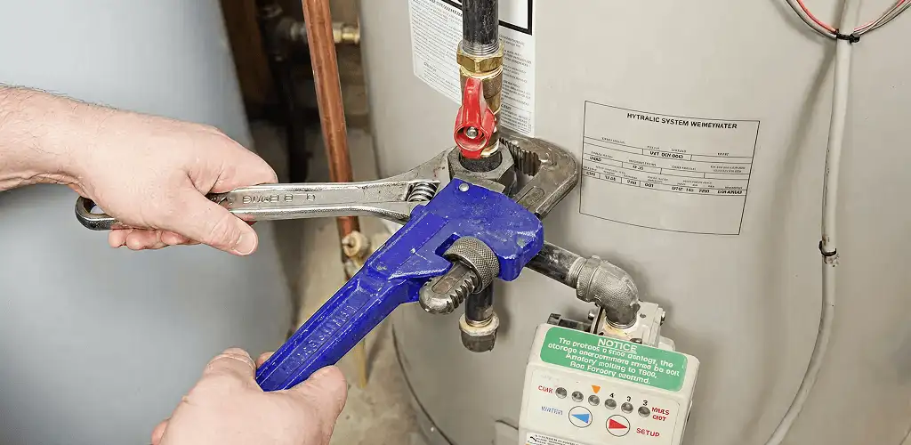 Water heater repair technician tightening the shutoff valve and supply line in Columbia, MO